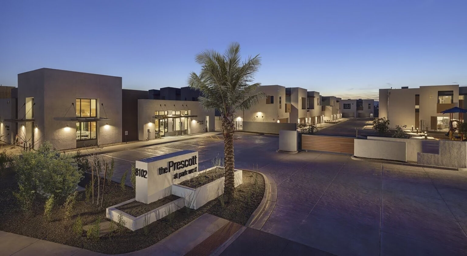 A modern residential complex named "The Prescott" featuring minimalist architecture, with well-lit pathways and a central palm tree, captured at dusk. Ideal for those seeking rental options, its sleek design is showcased perfectly in a single page template.